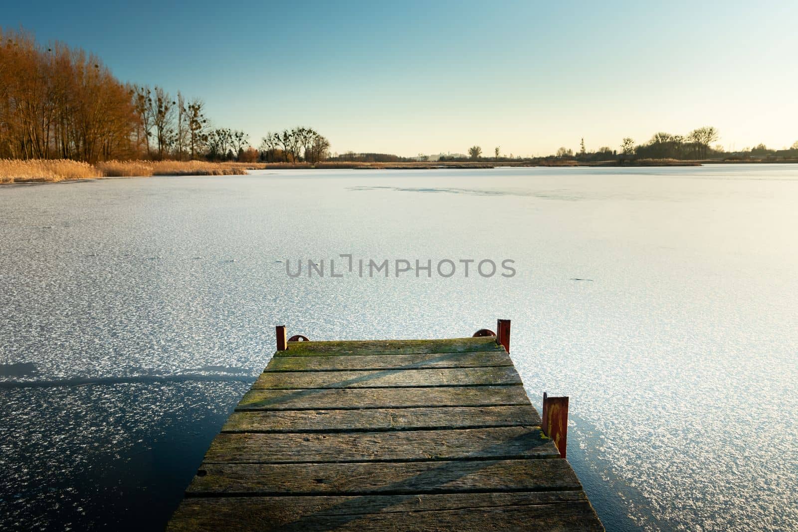 Wooden pier towards the frozen lake, winter landscape in Stankow, Poland