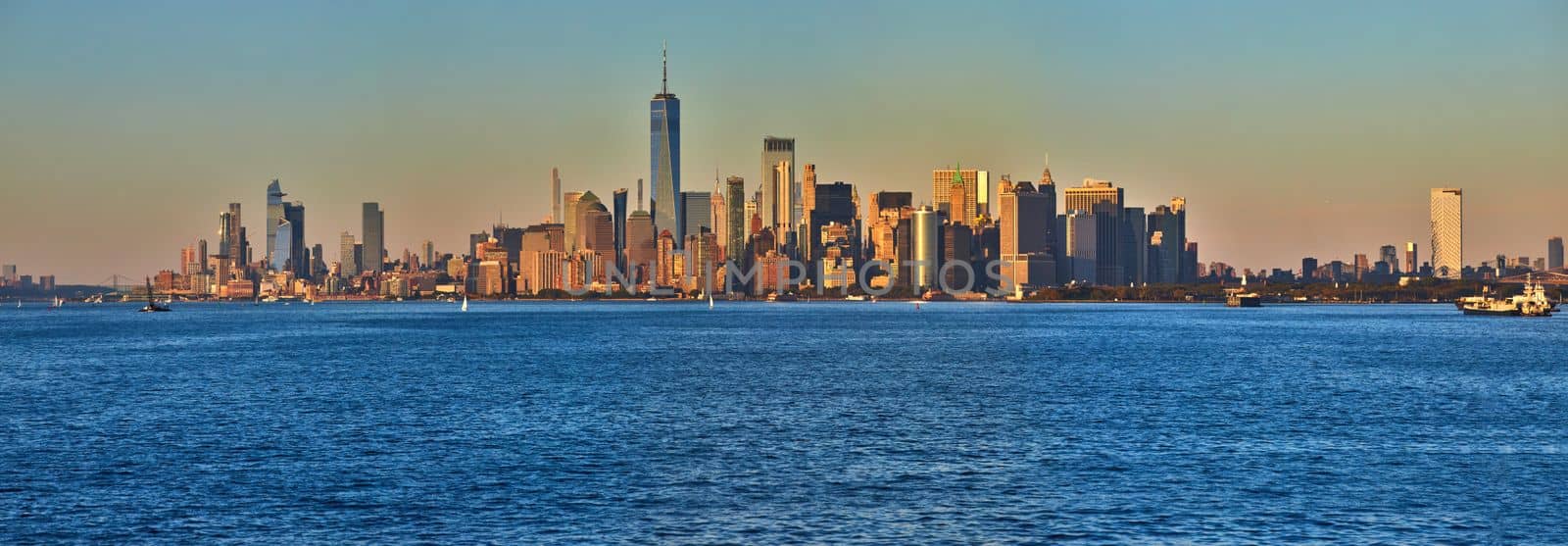 Image of Panoramic golden hour sunset from waters south of Manhattan New York City of skyline and One World Observatory