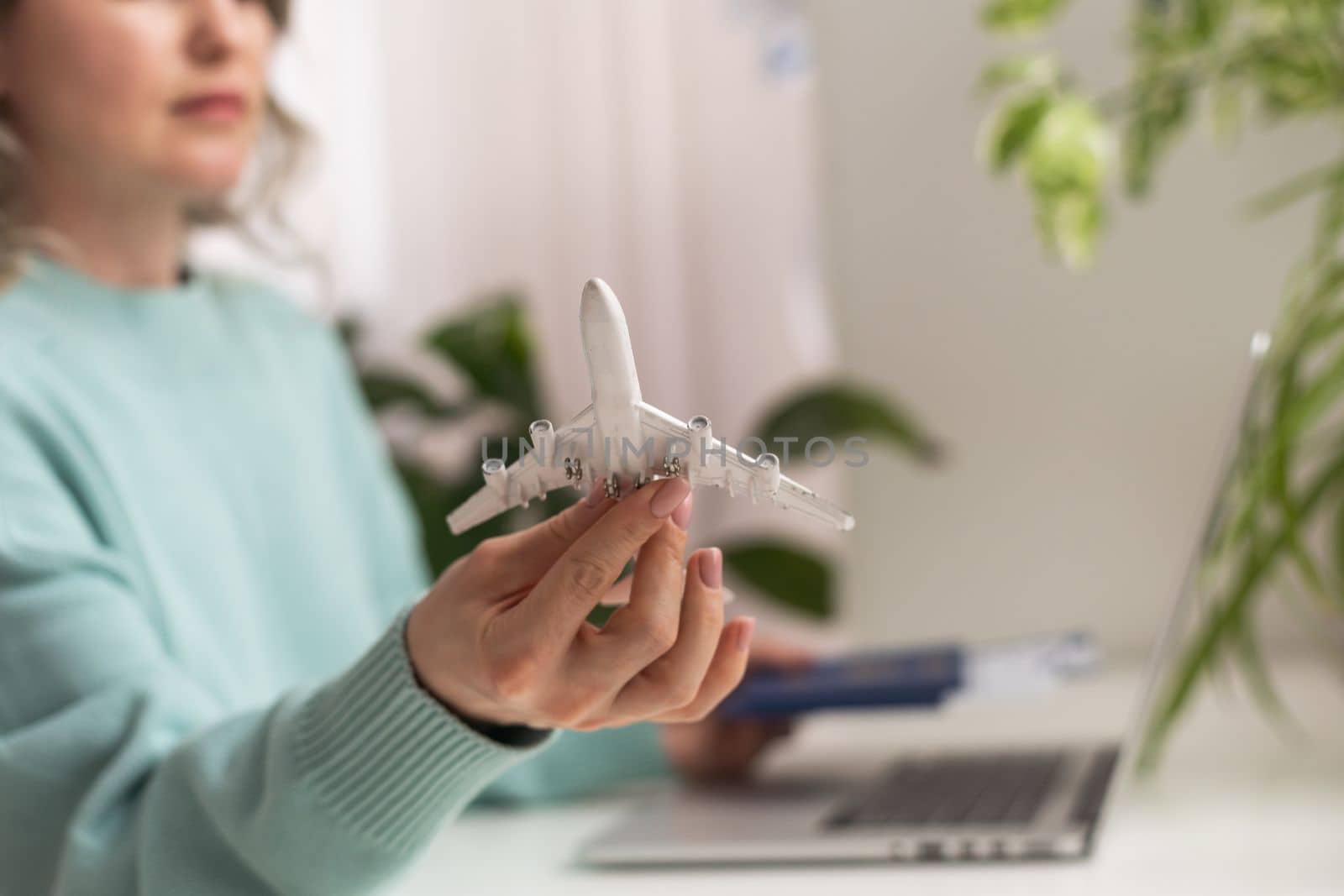 Positive happy woman going on summer holidays, sitting at office with toy plane and showing passport, having video call by Andelov13