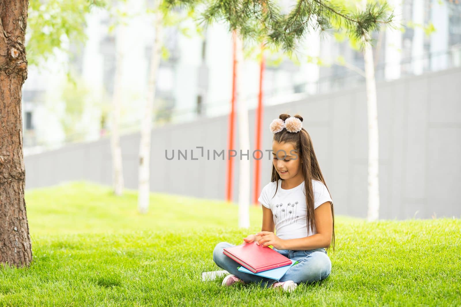 Little girl reading a book in the spring park.