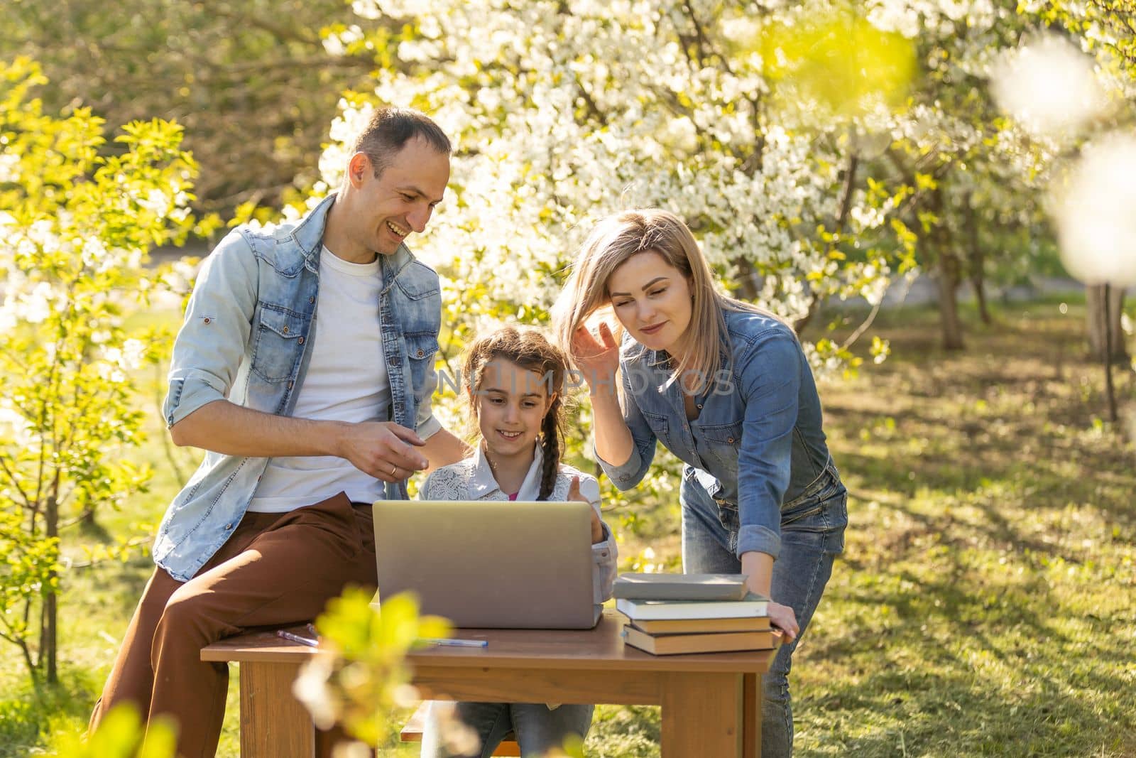 little girl with mom and dad studying on laptop outdoor by Andelov13