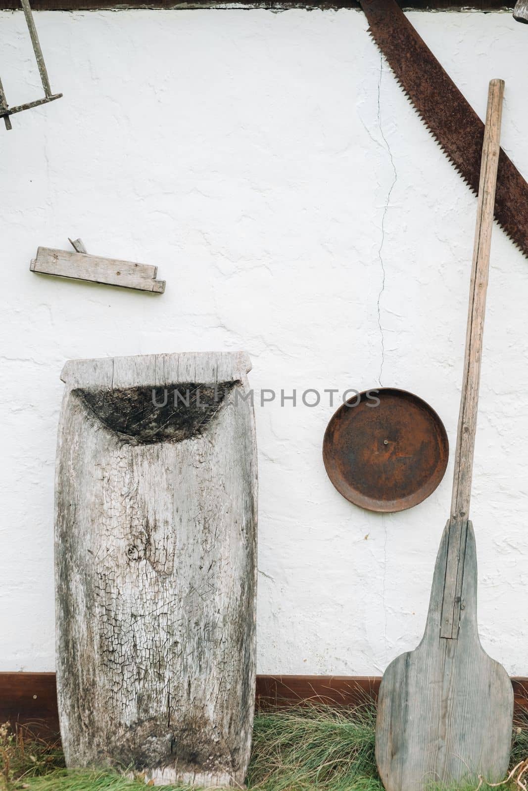 An old wooden wall of a house in the village and tools near the wall by Lobachad