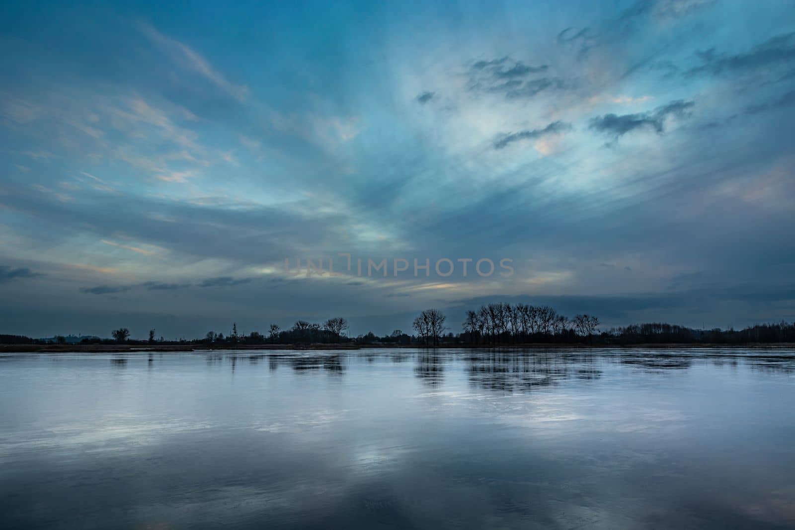 Picturesque evening clouds over the frozen lake, Winter landscape