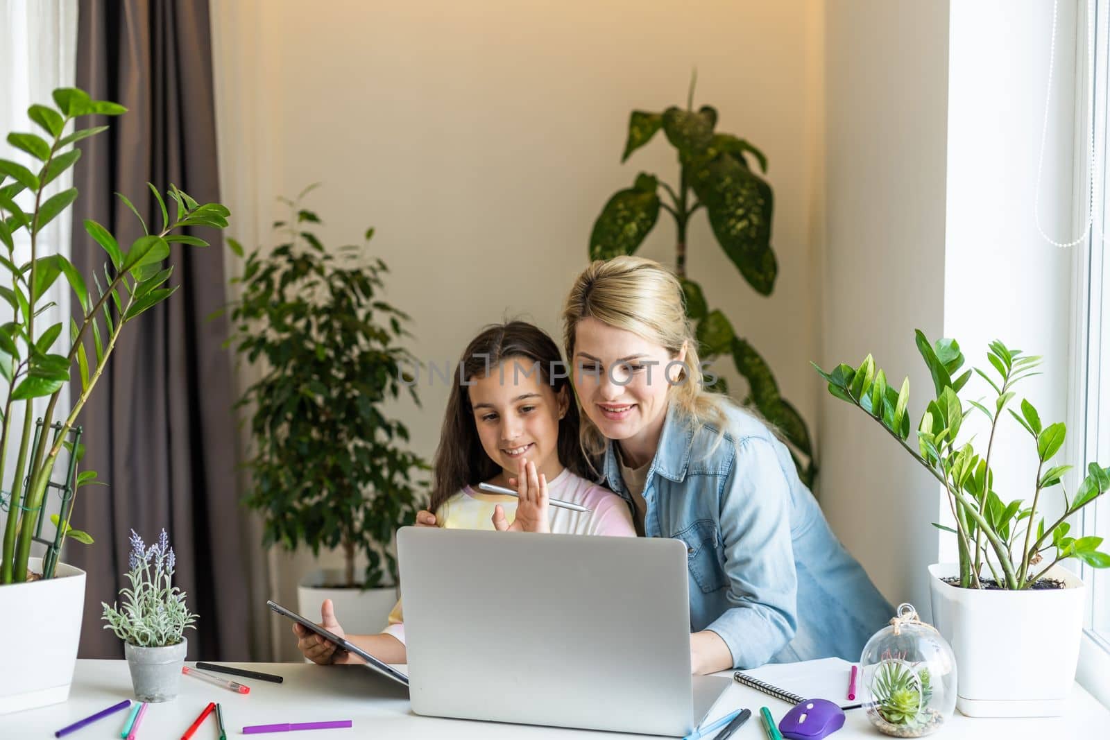 Happy mother with little kid daughter having fun online with application, watching video cartoons or playing game on laptop together, young babysitter or nanny teaching child girl to use computer.