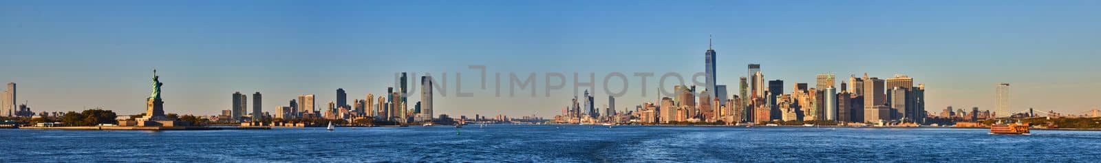 Wide panoramic view of southern Manhattan New York City and New Jersey with Statue of Liberty from waters near sunset by njproductions