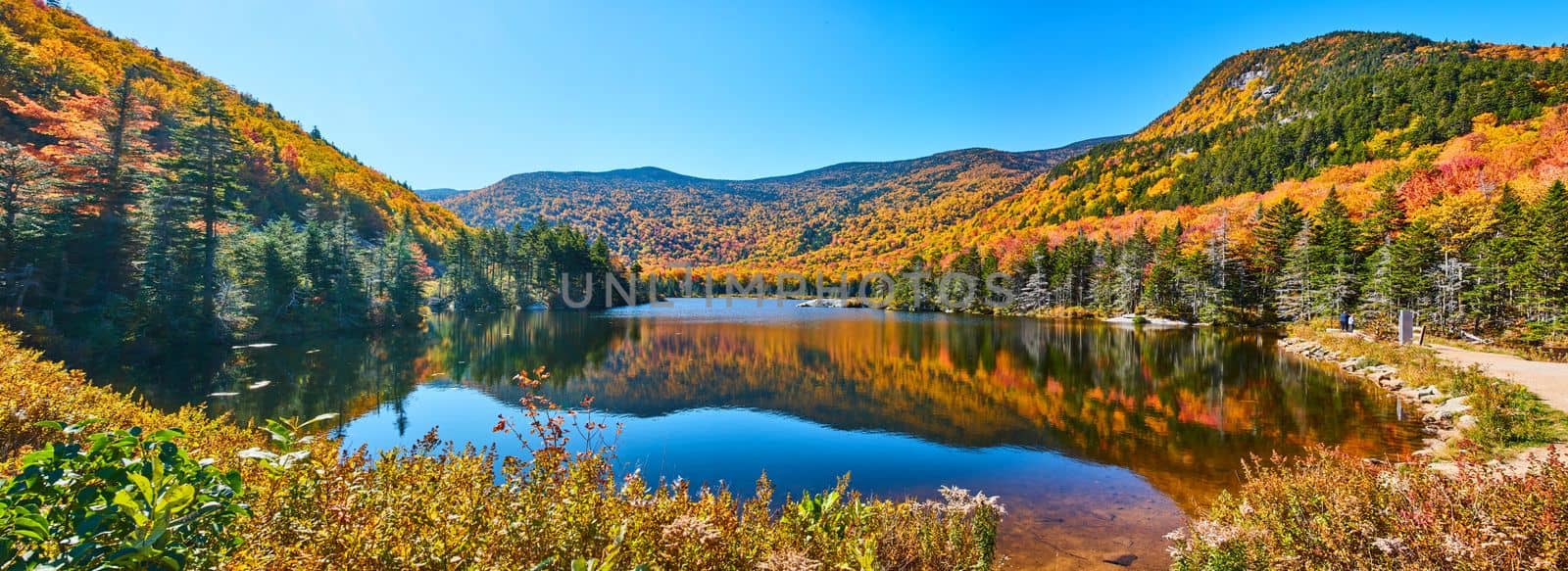 Image of Beautiful panorama of blue lake in New Hampshire mountains during peak fall foliage