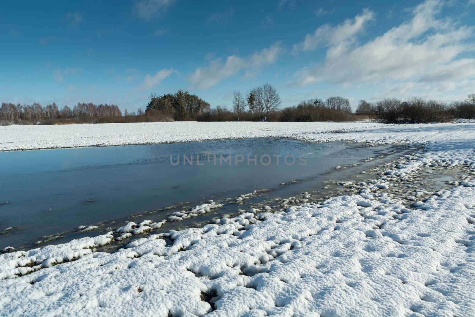 Frozen water and snow on the farmland, February day in eastern Poland