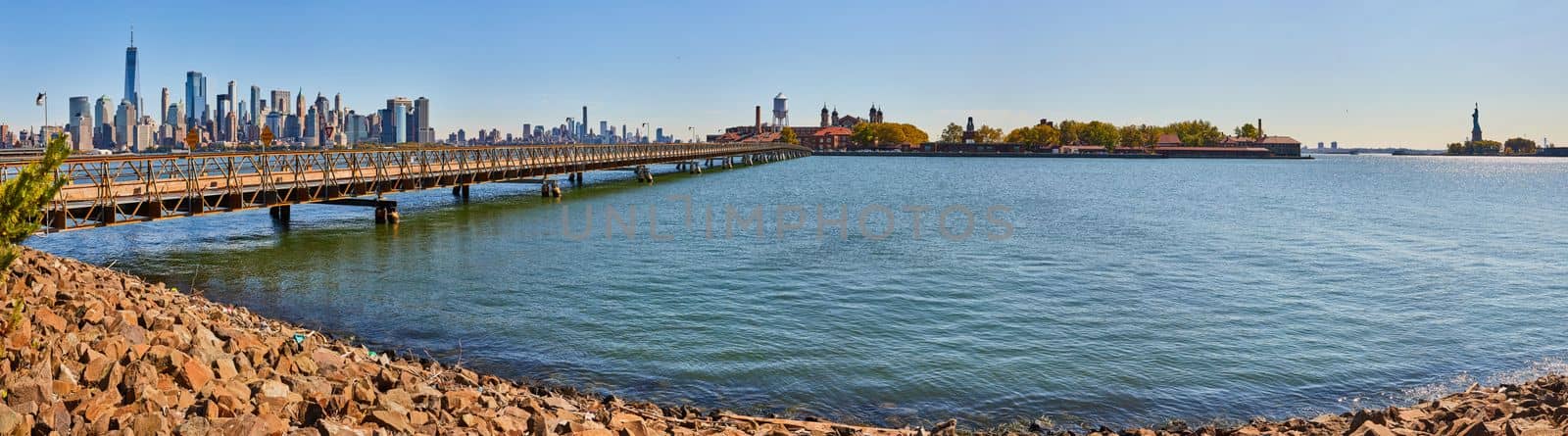 Panoramic view from New Jersey coast of Ellis Island, Statue of Liberty, and New York City skyline in distance by njproductions