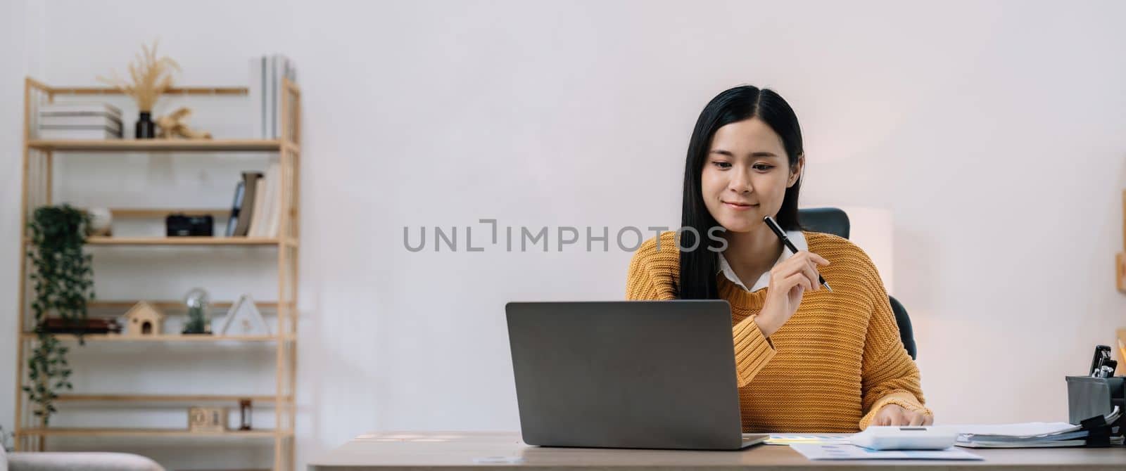 Young asian female work with financial papers at home count on calculator before paying taxes receipts online by phone. Millennial woman planning budget glad to find chance for economy saving money.