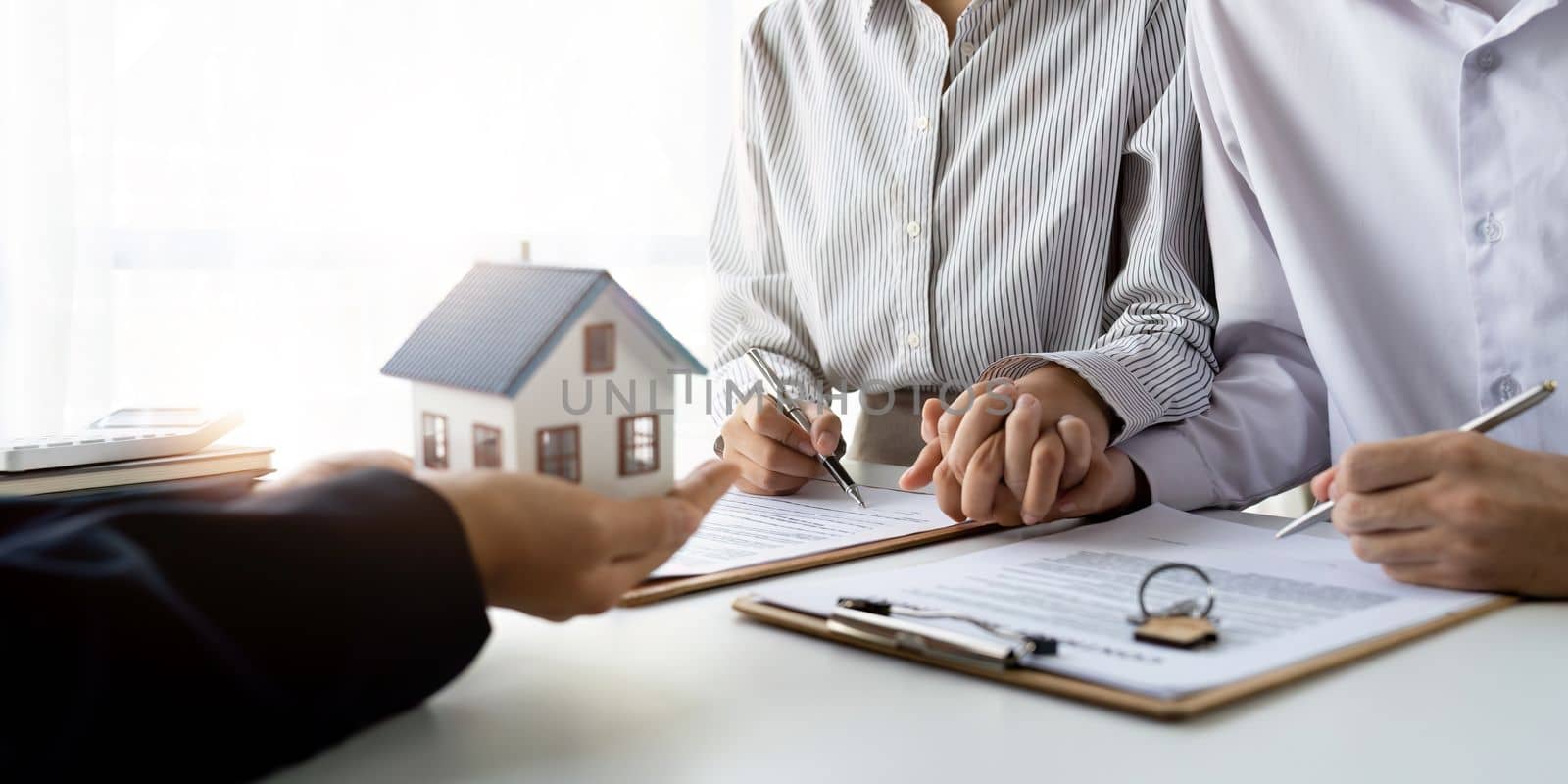 Real estate agent with couple closing a deal and signing a contract