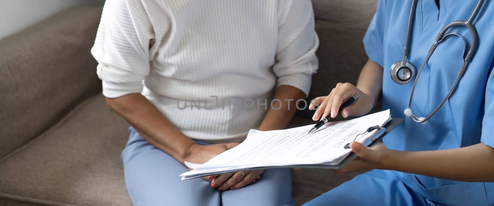 Close up female doctor holding application form while consulting elderly patient.