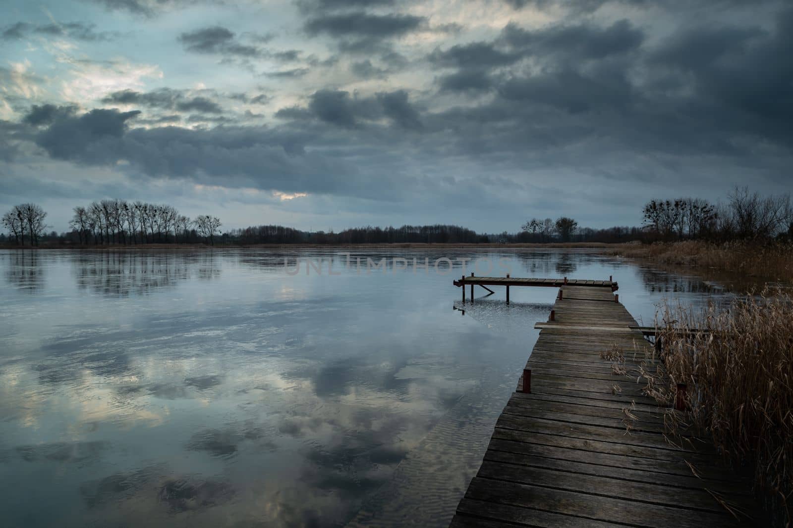 Wooden pier on the lake and cloudy sky