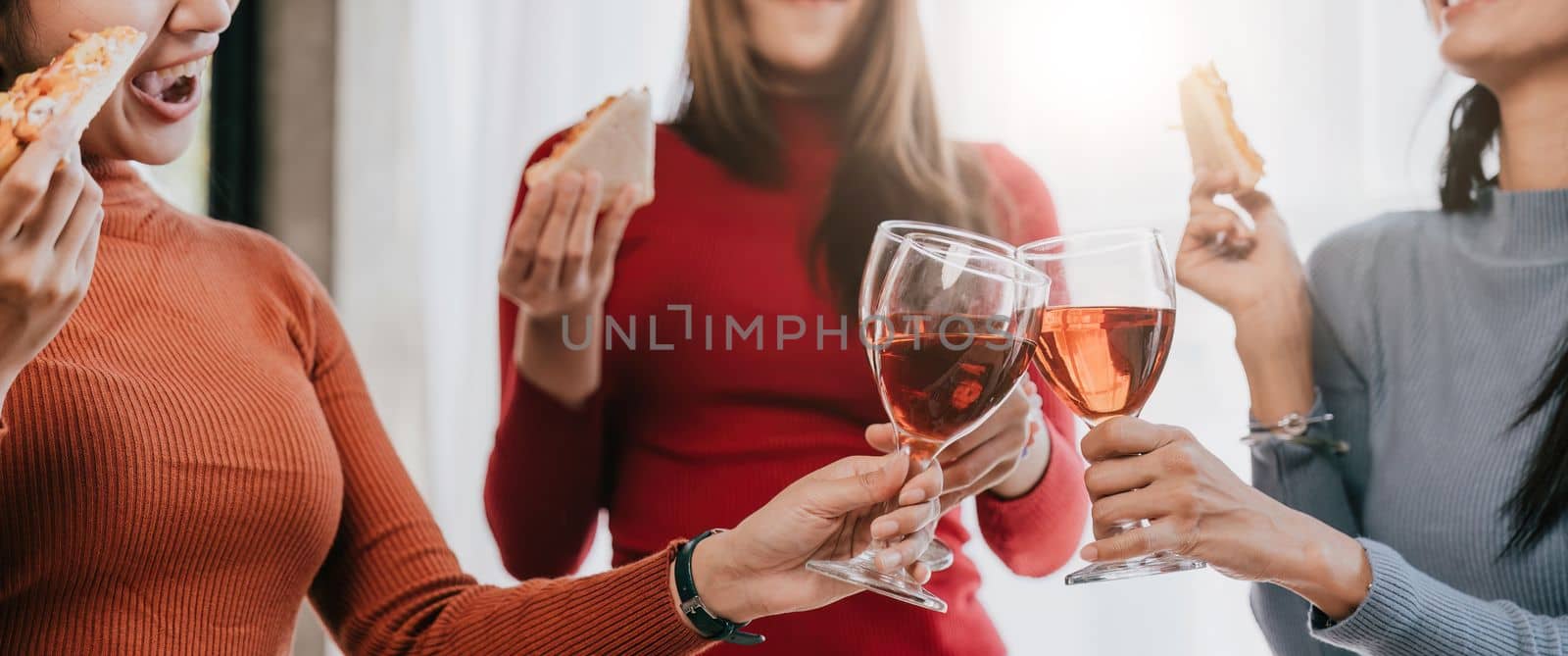 Group of Asian friends gather to celebrate Christmas with champagne and eating pizza at home. Joy of holiday party with friends or colleague concept.