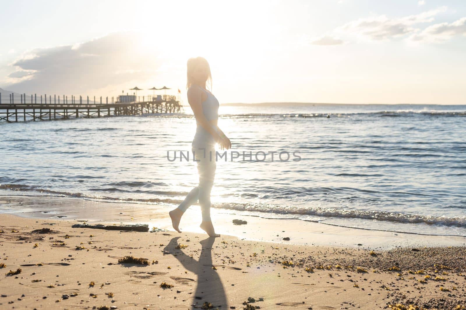 fitness woman running on a road by the sea. Sportswoman training on seaside promenade. by Andelov13