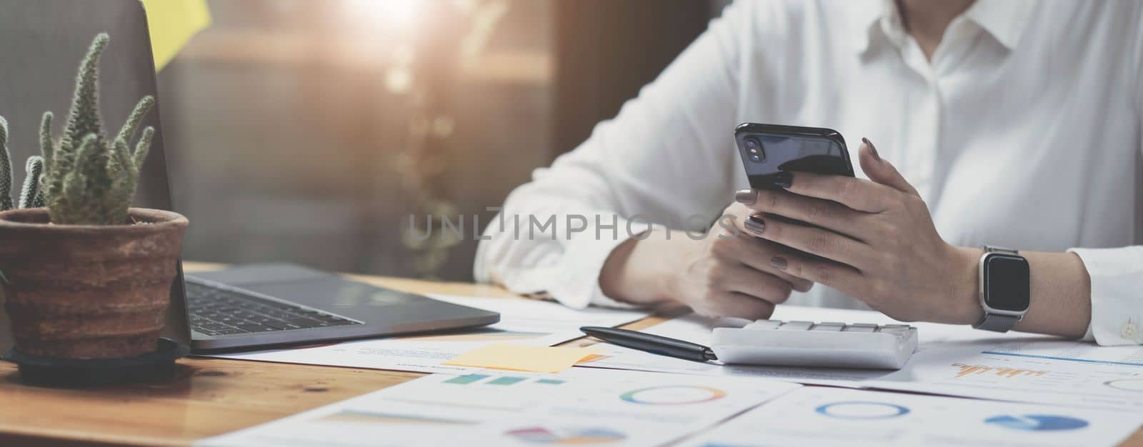 asian woman using phone in office. Small business entrepreneur looking at her mobile phone and smiling. by wichayada