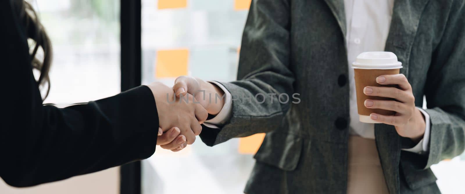 Welcome to our team. close up young modern women shaking hands while working in the creative office by nateemee