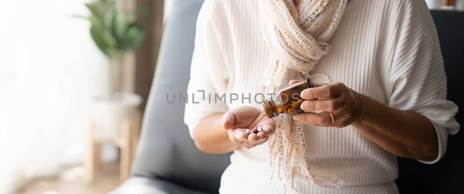Close up mature woman taking out pills from bottle, supplements or antibiotic, older female preparing to take emergency medicine, chronic disease, healthcare and treatment concept by nateemee