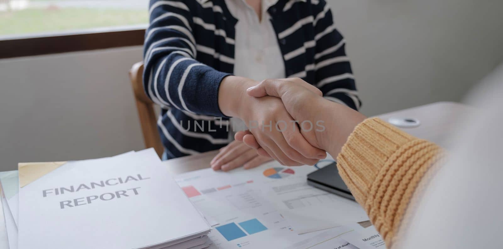 Business woman and partner shaking hands in office by wichayada