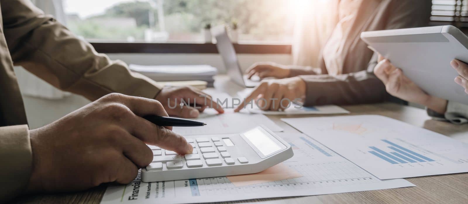 Close up Businessman and partner using calculator and laptop for calaulating finance, tax, accounting, statistics and analytic research concept by wichayada