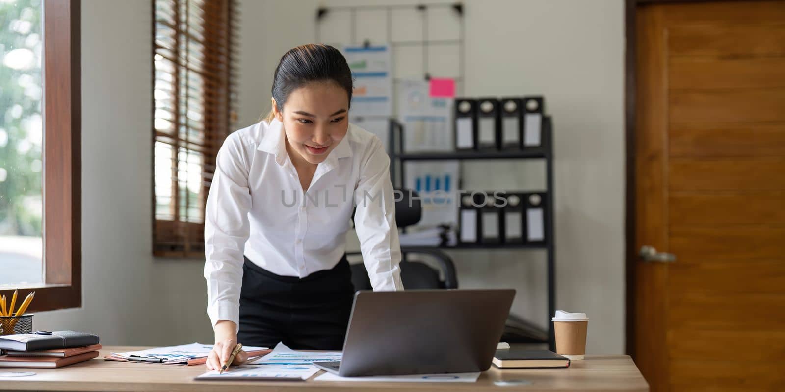 Beautiful Asian Businesswoman using on laptop for financial analysis
