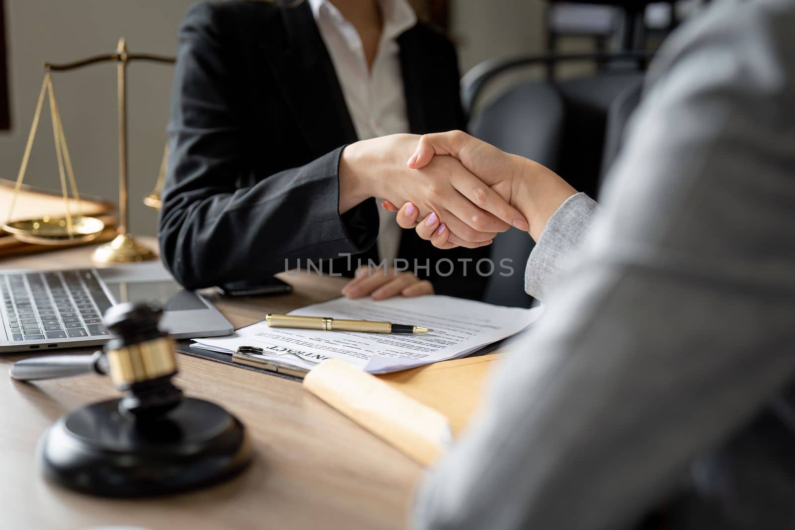 Gavel Justice hammer on wooden table with judge and client shaking hands after adviced in background at courtroom, lawyer service concept