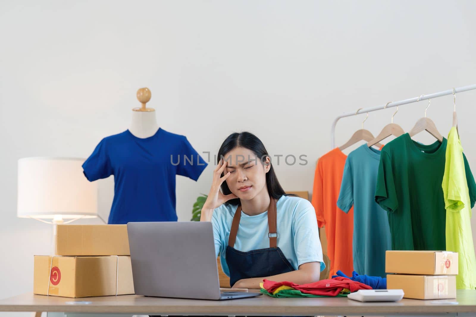 Stress serious asian woman doing clothing business selling online. she using laptop computer. online sell marketing delivery, SME e-commerce telemarketing concept by nateemee
