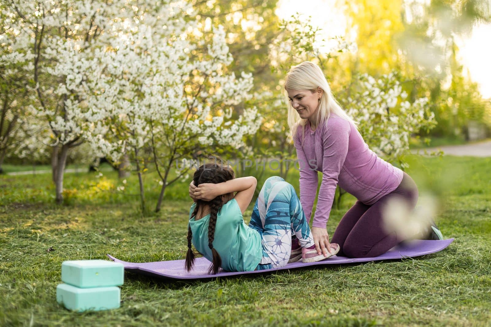Mother and her daughter outdoors doing yoga, healthy lifestyle. by Andelov13