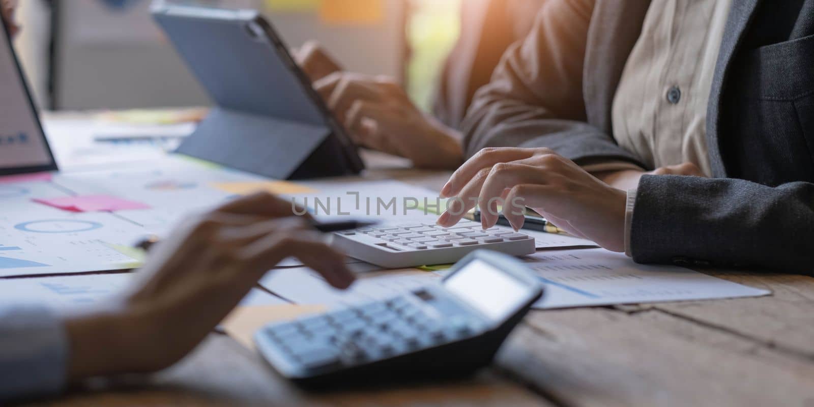 Accountant or bookkeeper working with calculator to calculate business data summary report, accountancy document and laptop computer at office, business meeting concept.