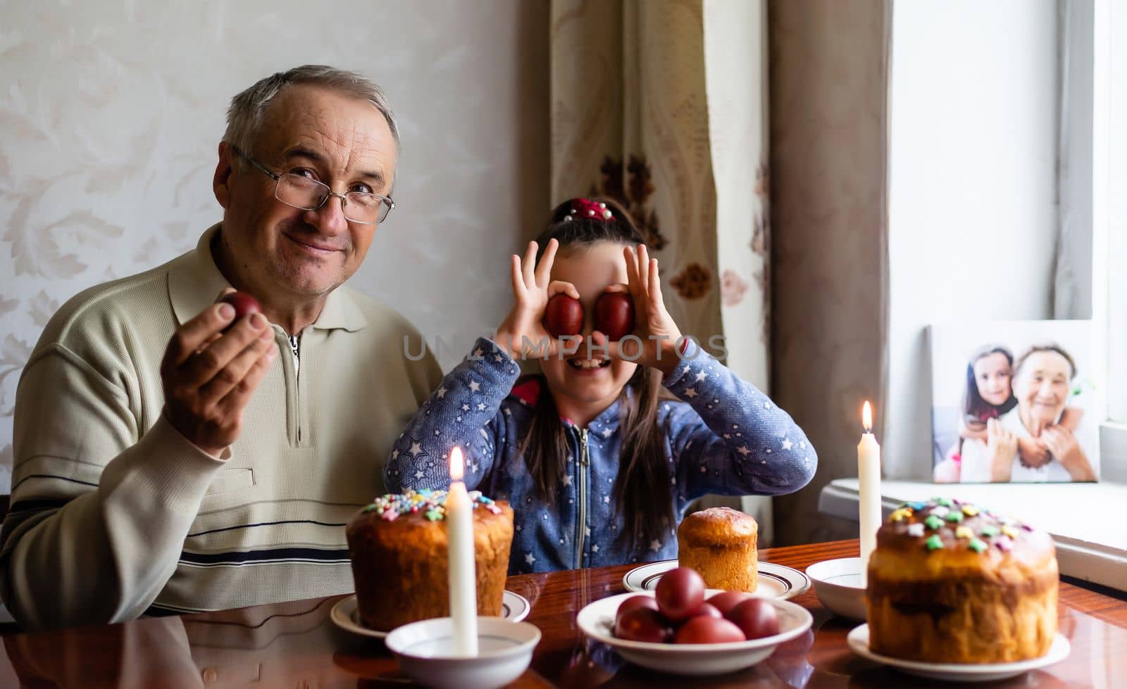 happy grandfather and granddaughter hold easter eggs in hand, folk game beats easter egg by Andelov13