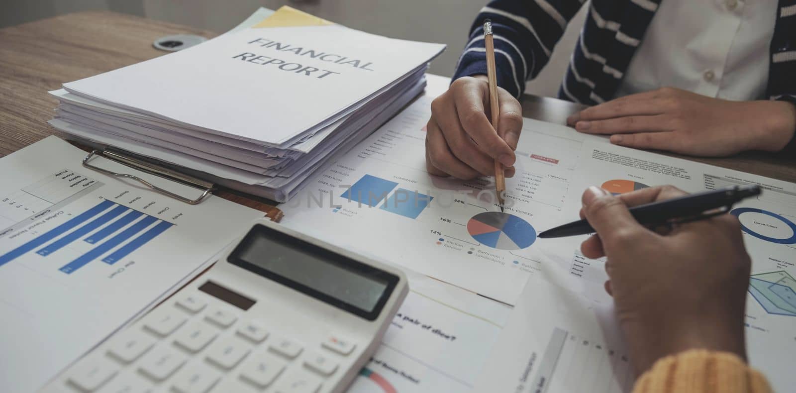 Close up photo of business working group of people are discussing together pointing at financial report, top or above view by wichayada