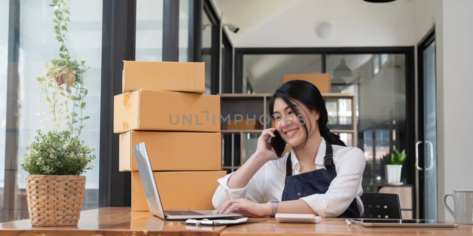 Happy young asian woman startup small business freelance with parcel box using laptop at home. Online marketing packing box delivery concept by nateemee