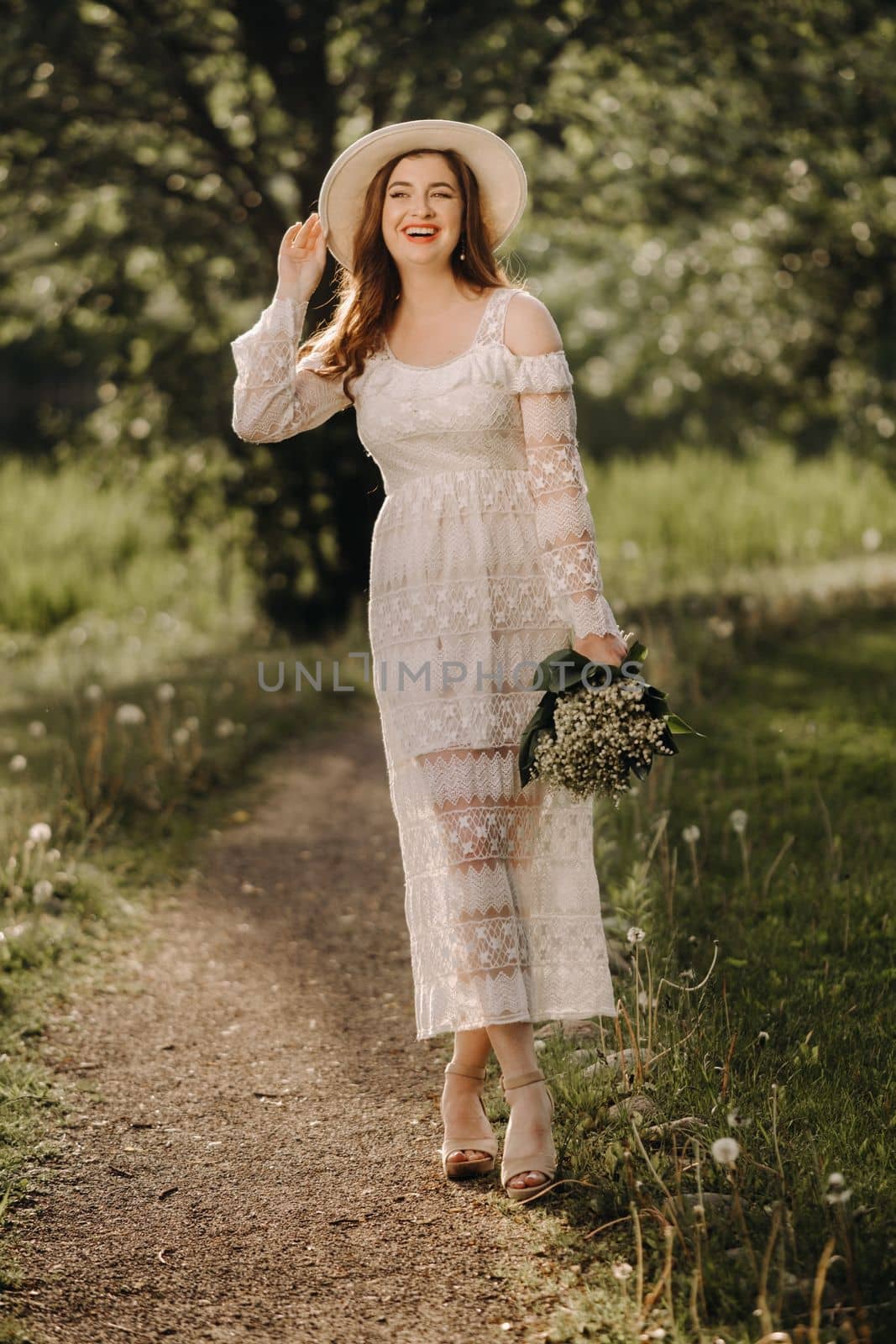 Portrait of a beautiful woman in a white dress and a hat with lilies of the valley. A girl in nature. Spring flowers by Lobachad