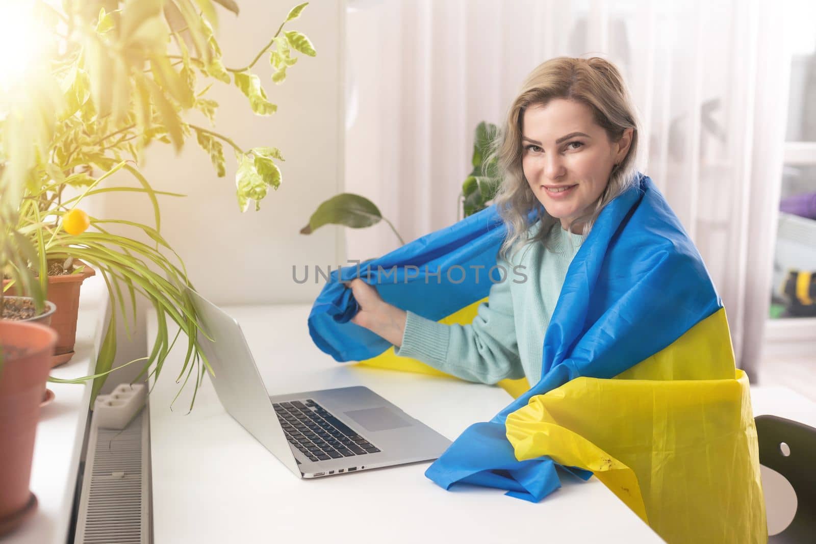 Ukrainian girl with the flag of Ukraine works on a laptop.