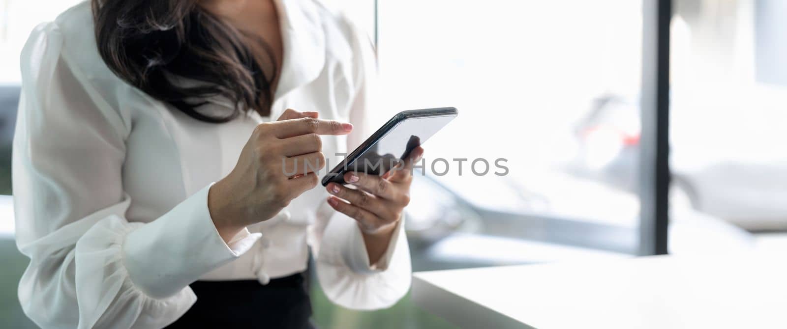 Close up young businesswoman using mobile phone in modern office