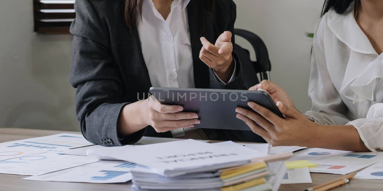 Close-up of hands using digital tablet, Two business colleague meeting to discussing the new project business strategy plan on wooden table in office. Briefing, brainstorming, consulting. by wichayada