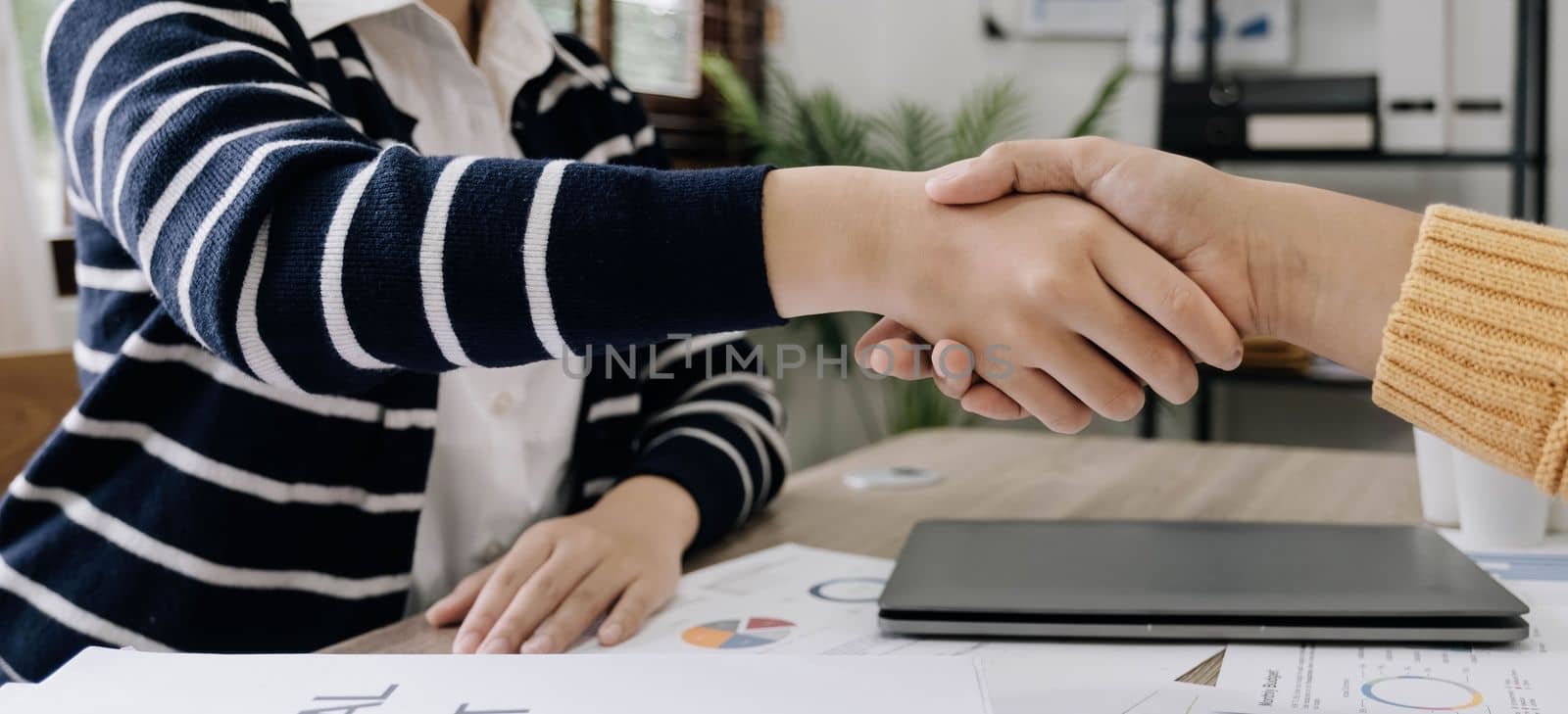 business people handshake at meeting table in office together. Young businessman and businesswoman workers express