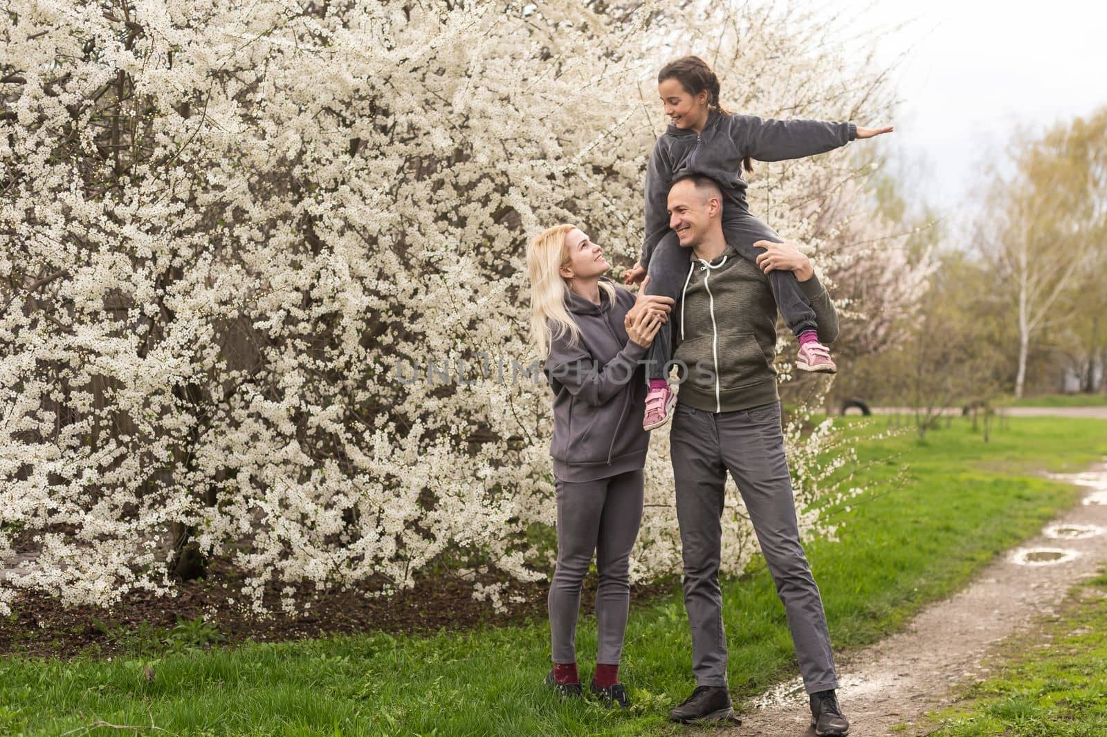 family having fun with flowering tree in blooming spring garden by Andelov13