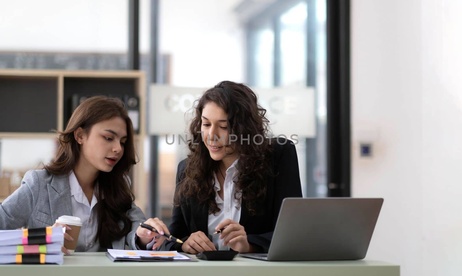 Two young Asian business woman talk, consult, discuss working with new startup project idea presentation analyze plan marketing and investment in the office..