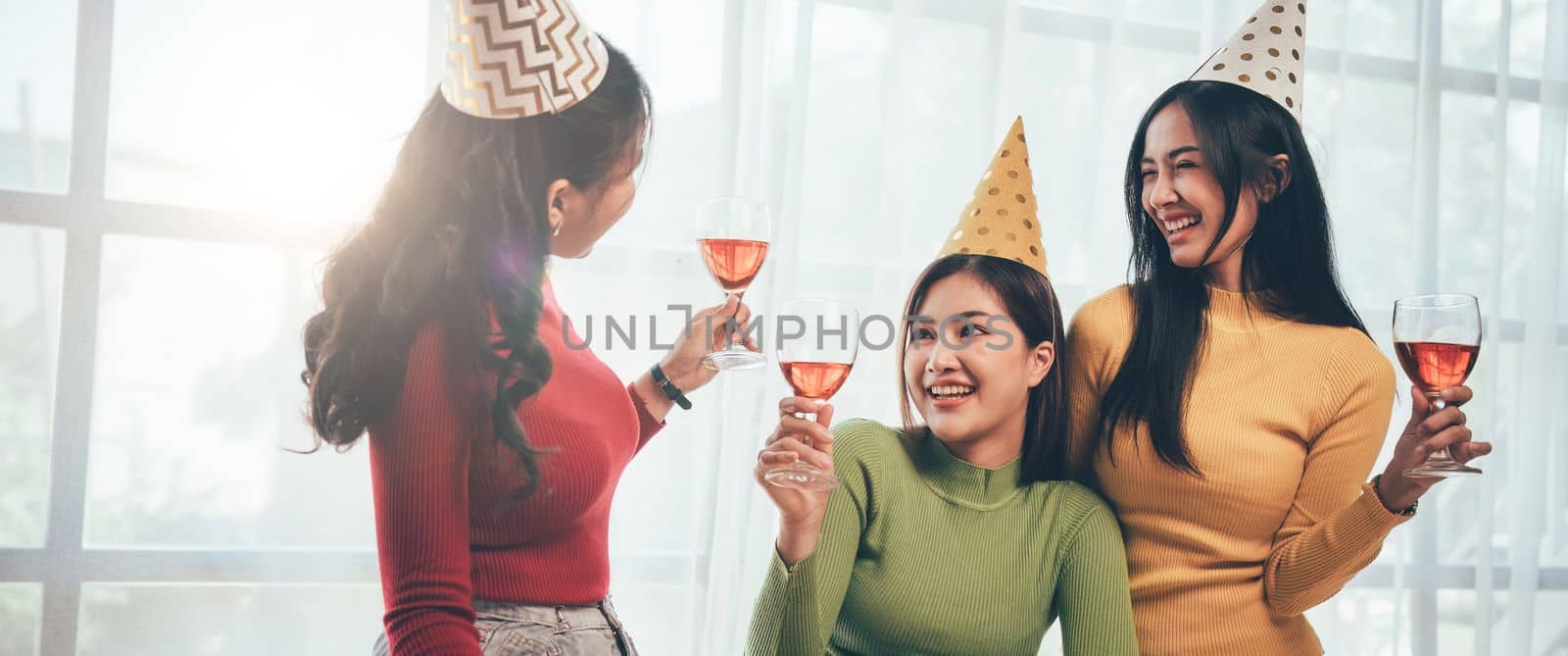 Group of Asian friends gather to celebrate Christmas with champagne and eating pizza at home. Joy of holiday party with friends or colleague concept.