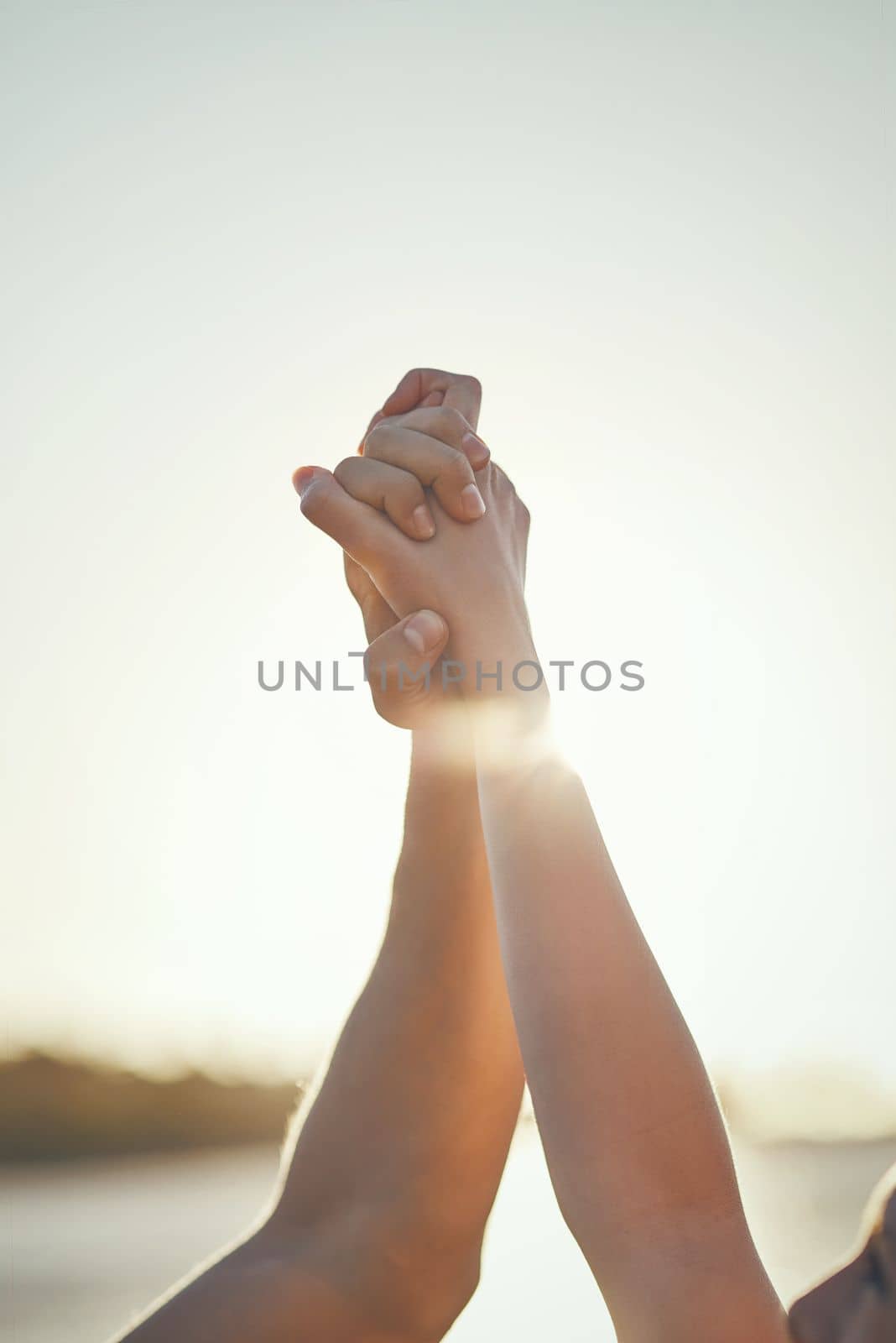 There is strength in unity. a couple holding hands and arms raised outdoors. by YuriArcurs