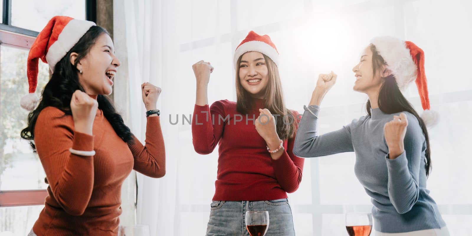 Group of Asian friends gather to celebrate Christmas with champagne and eating pizza at home. Joy of holiday party with friends or colleague concept.