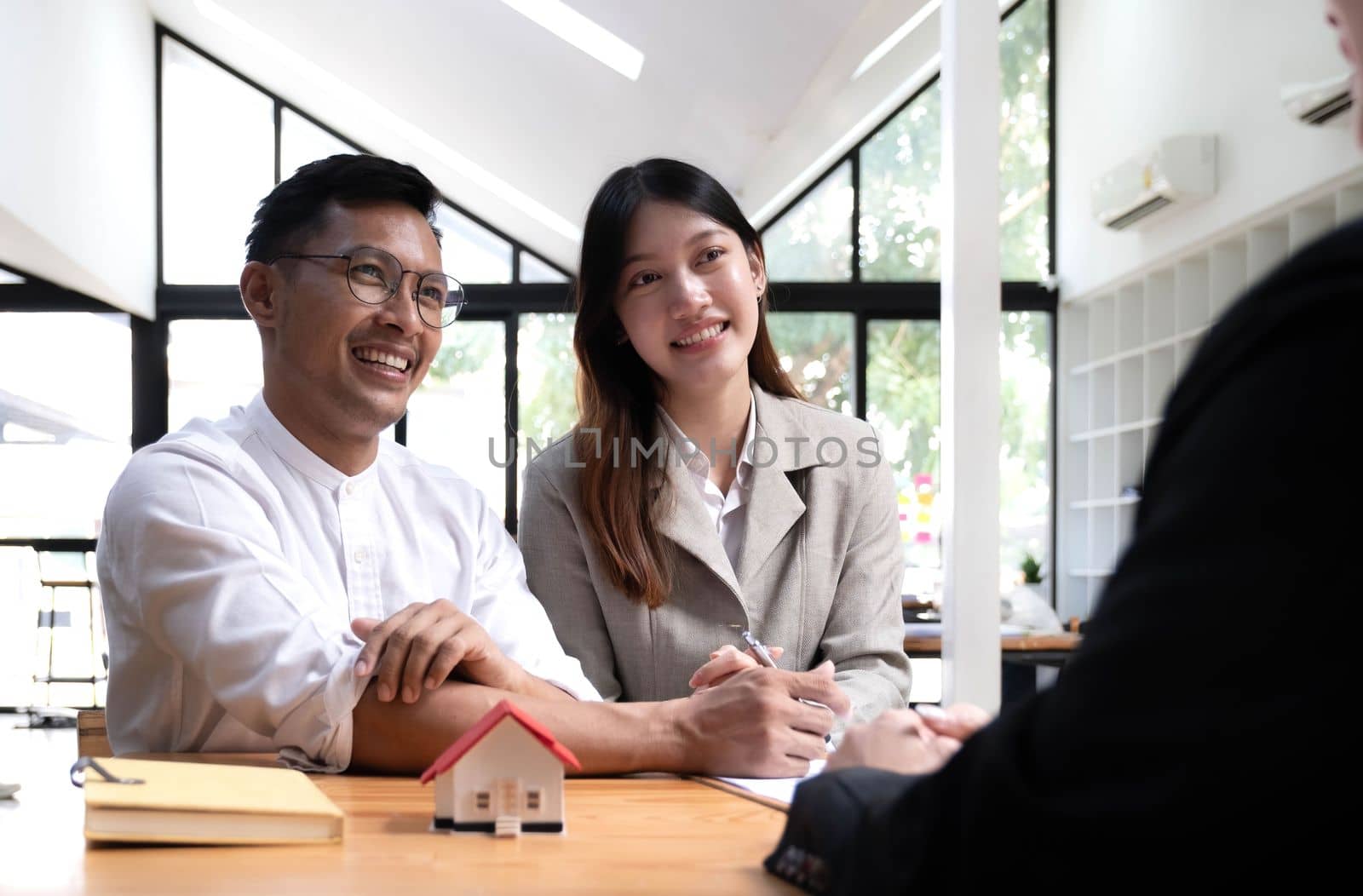 Horizontal view happy married couple wife asian ethnicity husband signing rental contract at meeting with realtor or landlord, first property purchase, mortgage and loan ownership concept.