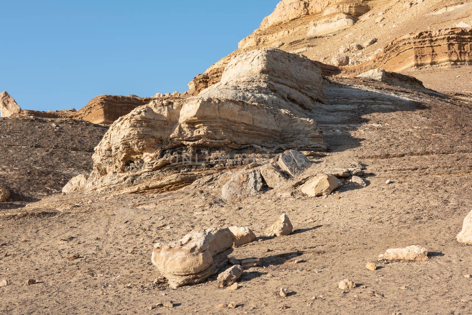 Rocky slope landscape in an arid desert environment with large pyramid mountain at top