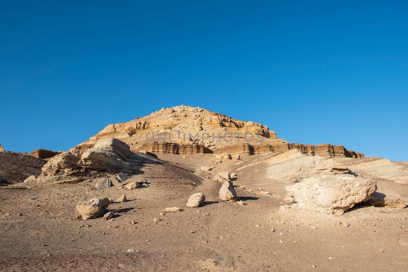 Rocky slope landscape in an arid desert environment with large pyramid mountain at top