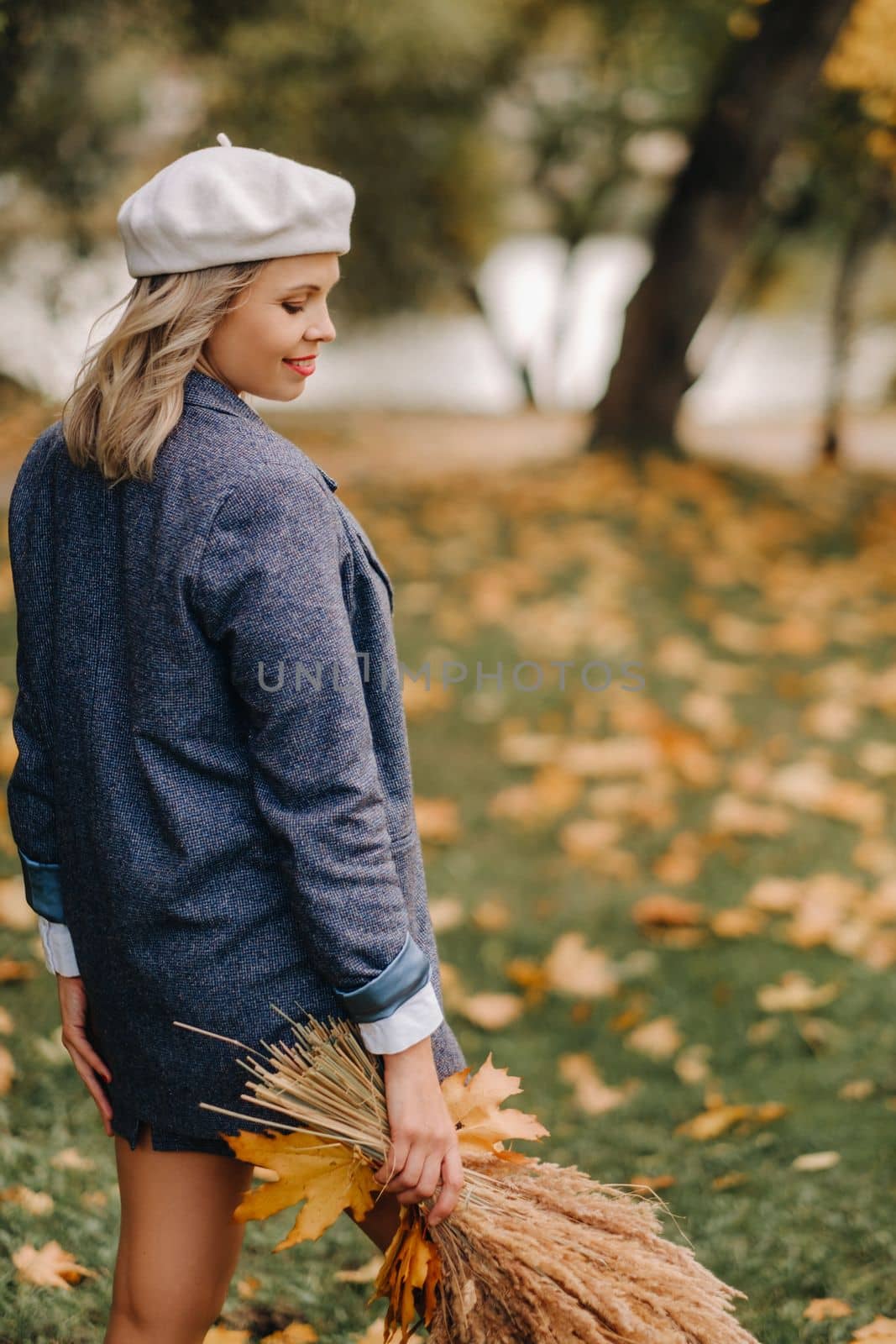 Portrait of a Girl in a jacket and birette with an autumn bouquet in an autumn park.