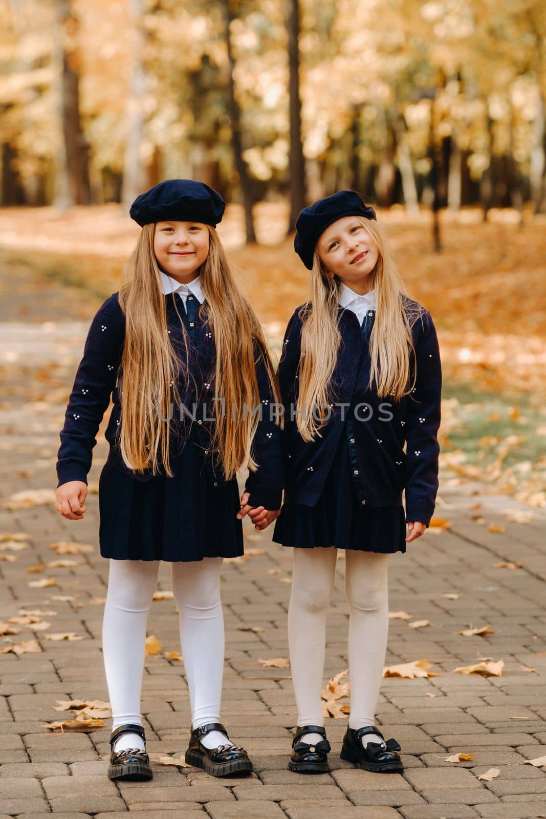 Happy children holding hands in a beautiful autumn park by Lobachad