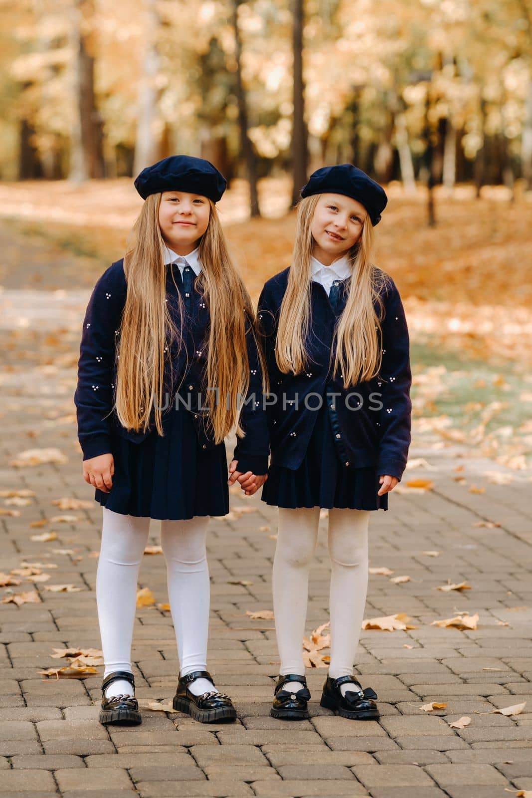 Happy children holding hands in a beautiful autumn park by Lobachad