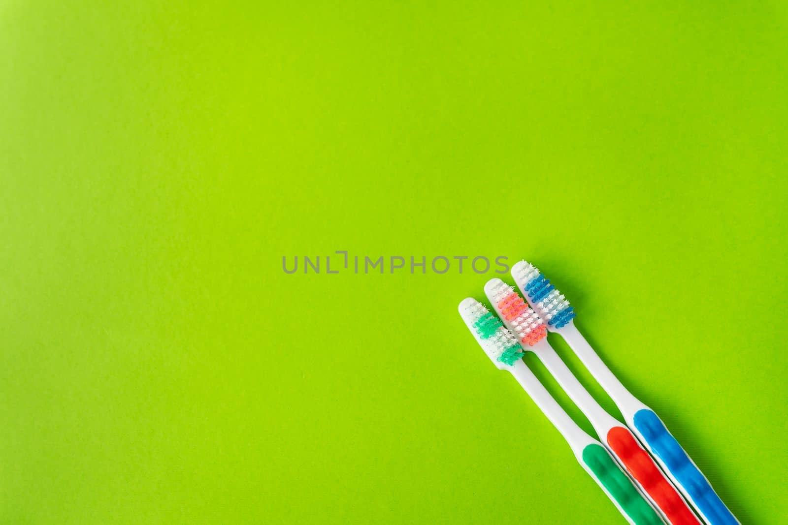 Multi-colored toothbrushes on a green background, the concept of dental care and hygiene. Place for an inscription. by sfinks