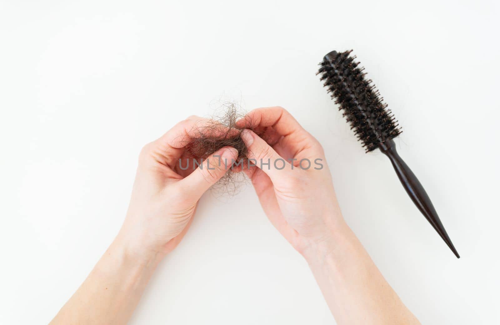 Hair loss in comb, daily serious hair loss problem, on white background. The girl holds the fallen hair in her hands