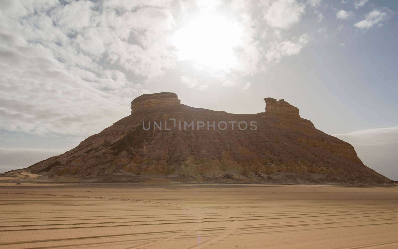 Landscape scenic view of desolate barren western desert in Egypt with two headed mountain against sun background